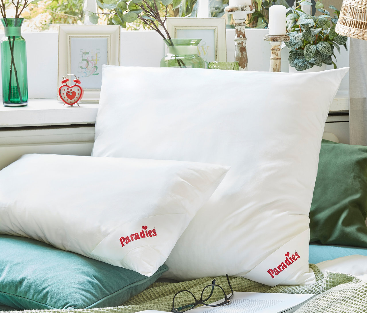 Zwei weiße Paradies Faserkissen »Softy Winterhude« in 80 x 80 cm und 40 x 80 cm liegen auf Kissen und einer Decke.