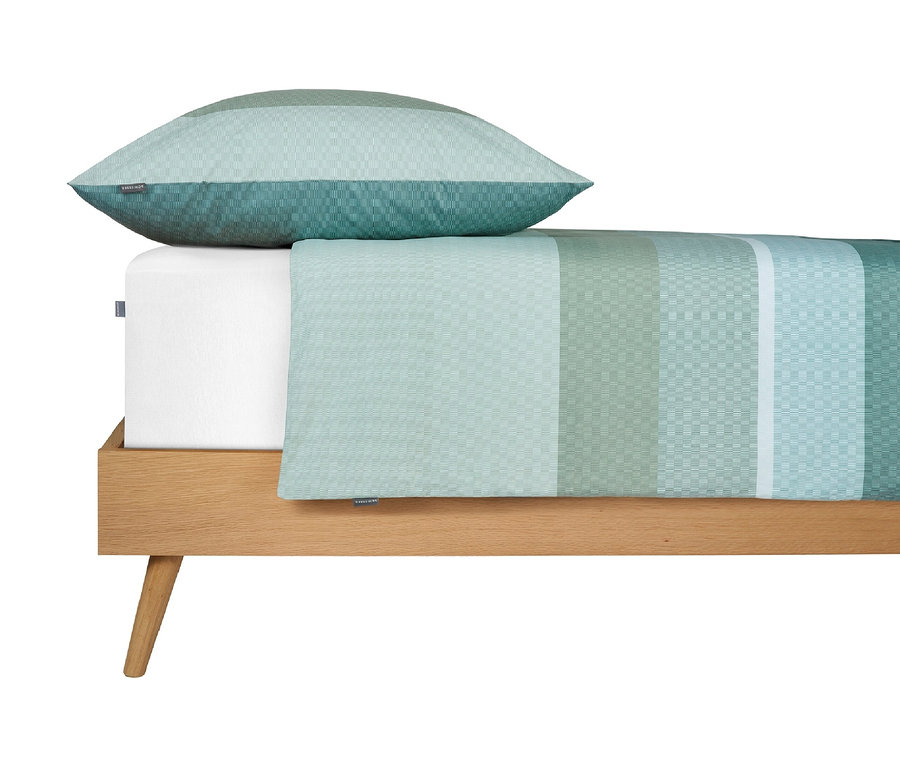 Bett mit grün gestreifter Bettwäsche und passendem Kopfkissen.