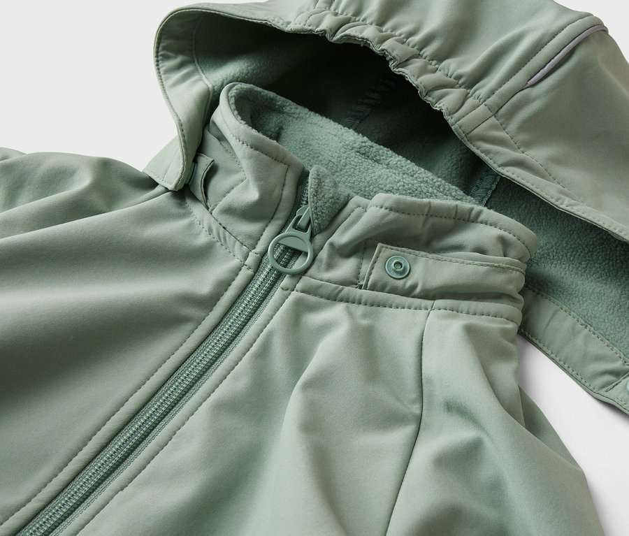 Nahaufnahme einer hellgrünen Jacke mit Kapuze, Reißverschluss und Druckknopf.