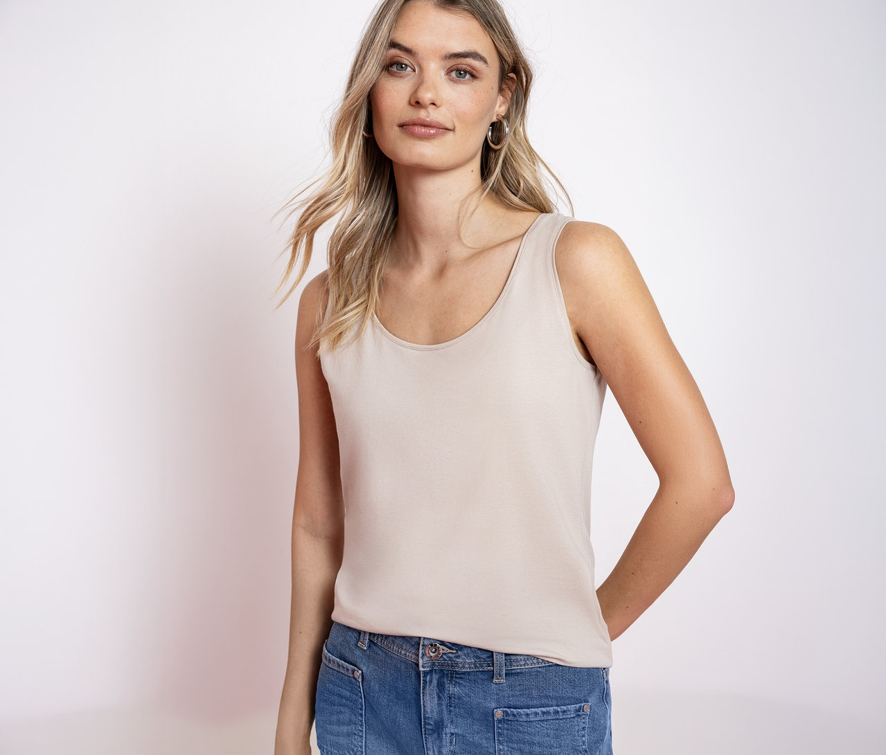 Frau mit blonden Haaren trägt ein Street One Basic-Top und Jeans.