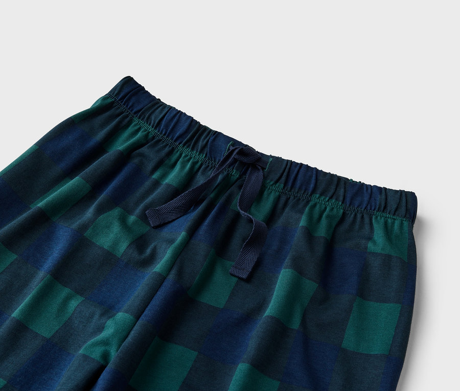 Nahaufnahme einer karierten Pyjamahose in Grün und Blau mit Kordelzug am Bund.