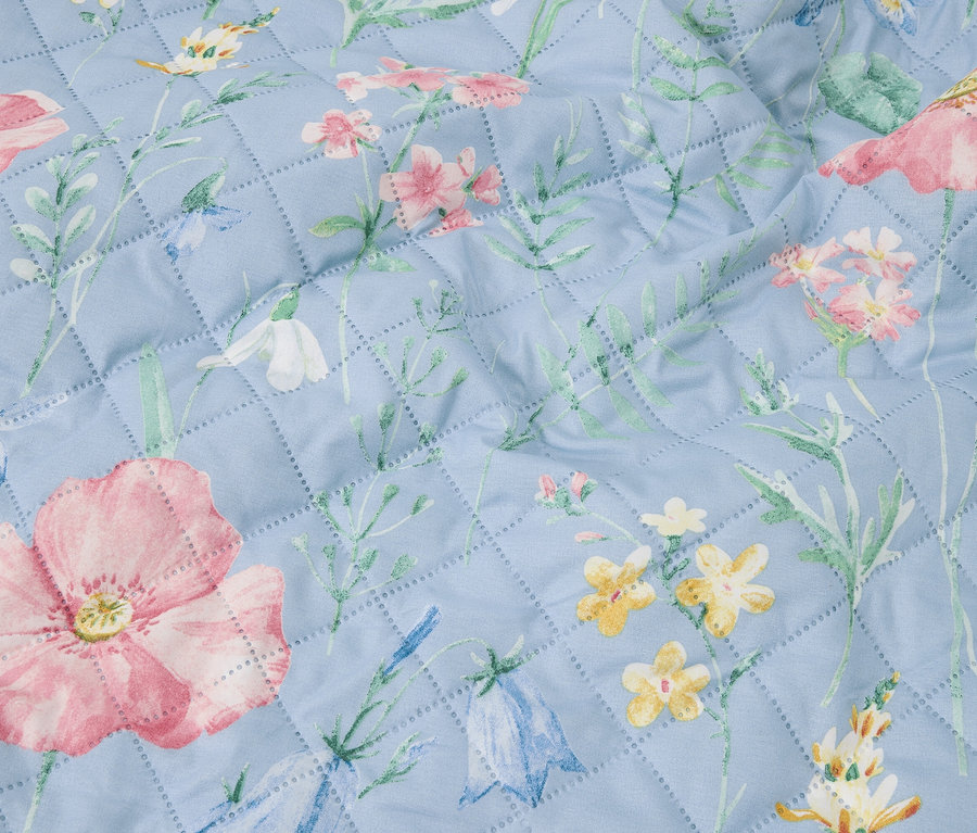 Nahaufnahme einer hellblauen Steppdecke mit Blumenmuster.