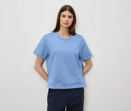 Frau trägt ein hellblaues T-Shirt und marineblaue Shorts.