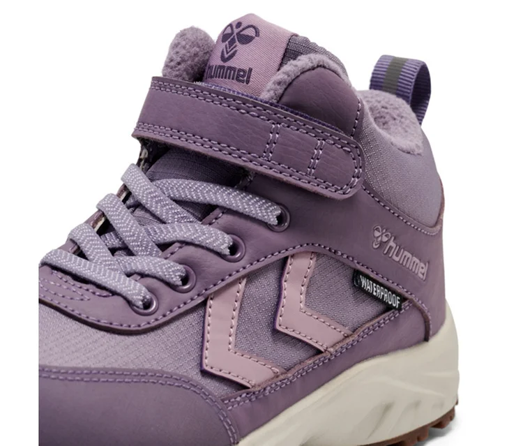 Nahaufnahme eines lila hummel® Turnschuhs »Root Tex Jr« mit hellvioletten Chevrons, Schnürsenkeln und Klettverschluss, mit "WATERPROOF"-Etikett und beiger Sohle.
