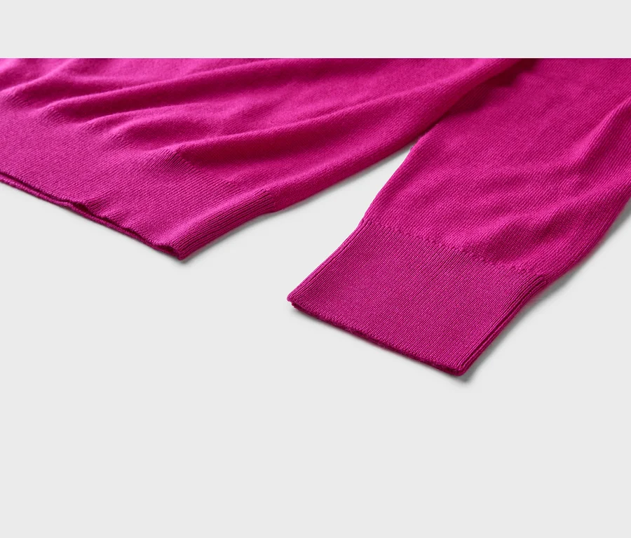 Nahaufnahme eines fuchsiafarbenen Strickpullovers mit gerippten Bündchen und Saum auf hellem Hintergrund.