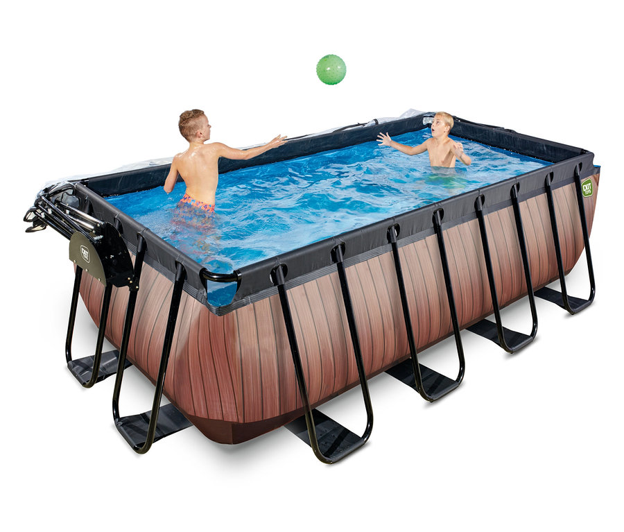 Zwei Jungen spielen mit einem grünen Ball in einem rechteckigen EXIT Pool-Set in Holzoptik. Der Pool hat schwarze Stützrahmen.