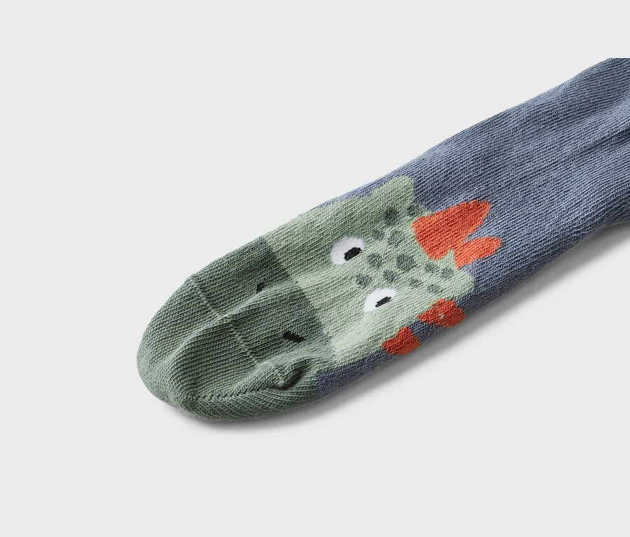 Nahaufnahme einer grauen Socke mit einem grünen Krokodil-Motiv und orangefarbenen Details.