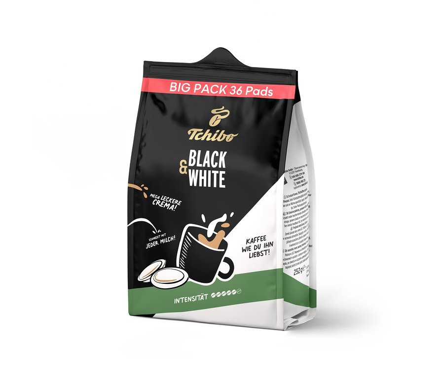 Schwarze und weiße Verpackung der Tchibo BLACK & WHITE Pads mit rotem Banner "BIG PACK 36 Pads". Abbildung einer Tasse Kaffee mit Milch und zwei Pads, dazu Texte wie "MEGA LECKERE CREMA!" und "SCHMECKT MIT JEDER MILCH!".