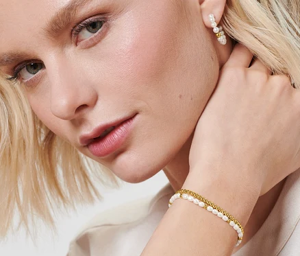 Blonde Frau trägt Creolen mit Glasperlen und Armband-Set mit Glasperlen.