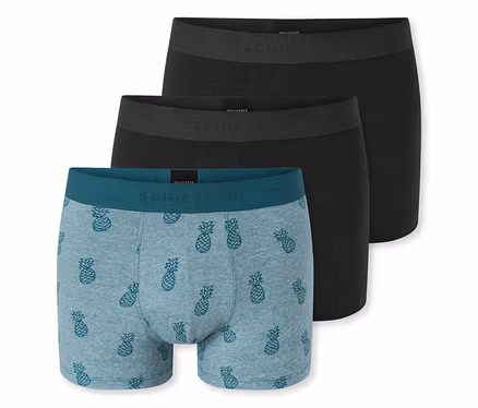 Drei Herren-Boxershorts liegen gestapelt auf einem weißen Hintergrund; die oberen zwei sind schwarz, die untere ist hellblau mit Ananas-Muster und einem türkisen Bund.