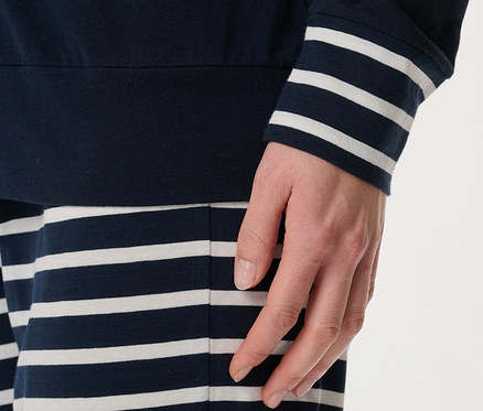 Detailaufnahme eines Damenpyjamas mit marineblauem Langarmshirt mit weißen Streifen und gestreifter Hose.