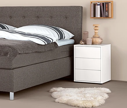 Boxspringbett mit Boxspring-Nachttisch und Dekorationen.