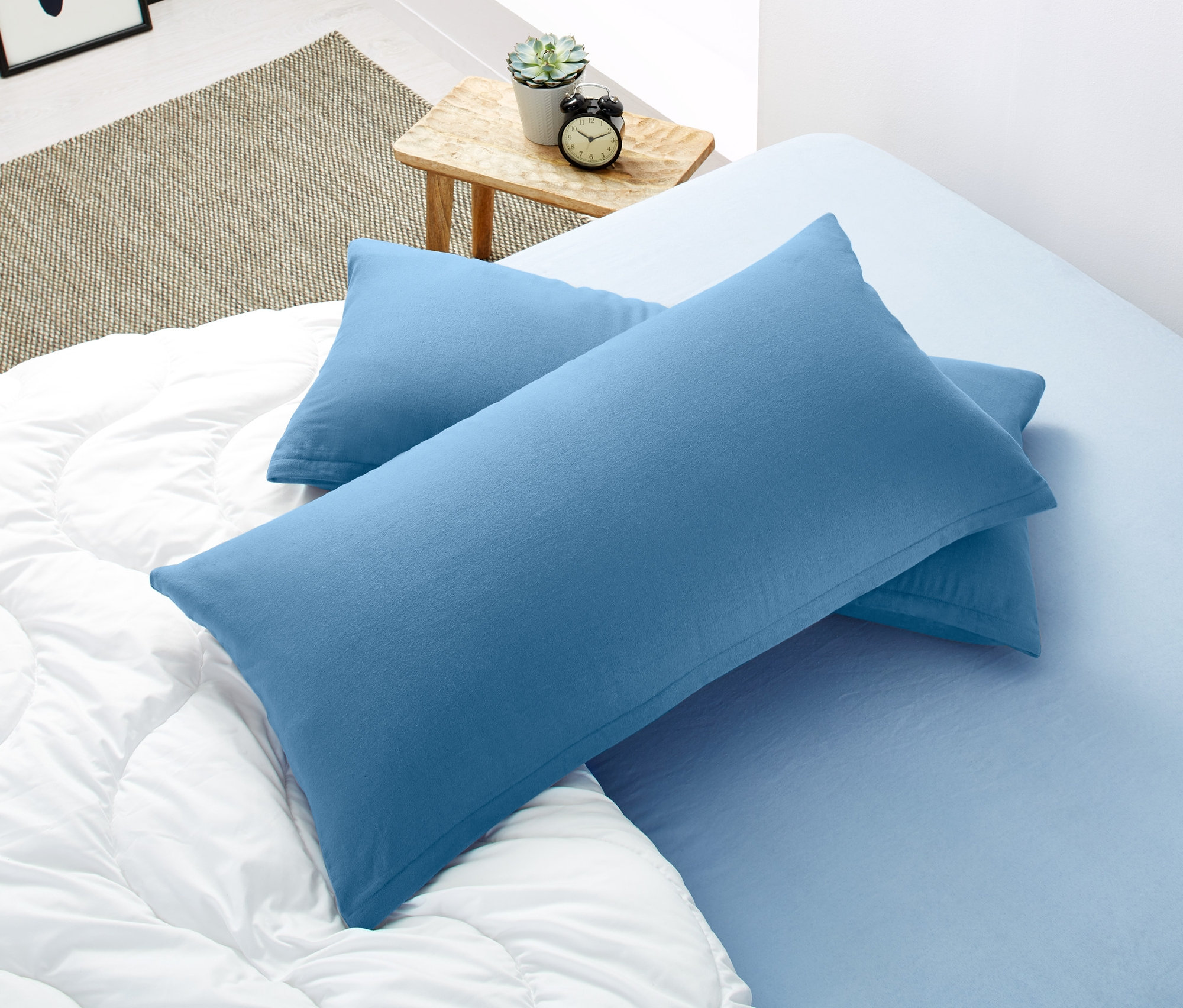 Zwei blaue Biber-Kopfkissenbezüge (je ca. 80 x 40 cm) liegen auf einer weißen Steppdecke.