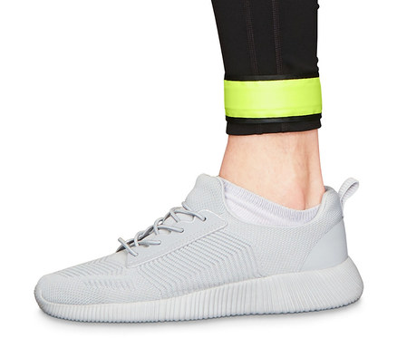 Bein in schwarzen Leggings und grauem Schuh. Am Bein sind 2 LED-Schnappbänder zu sehen.