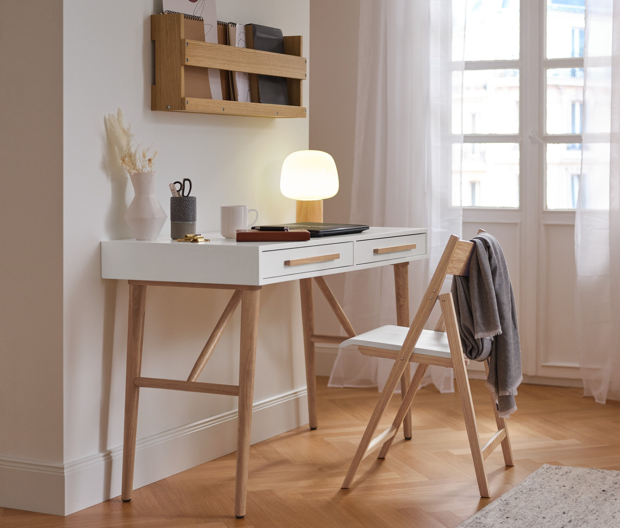 Ein weißer Sekretär »Eklund« mit Schubladen steht neben einem Stuhl an der Wand.