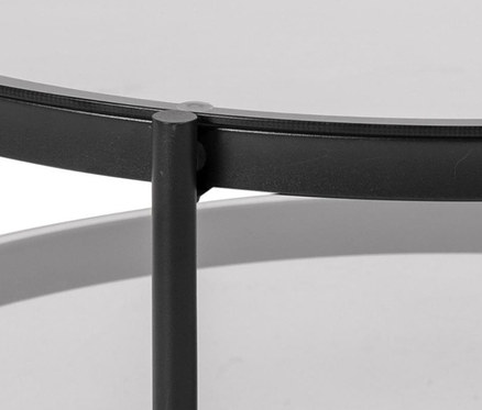 Detailansicht eines runden Glas-Couchtisches mit schwarzem Rahmen und grauem Unterboden.