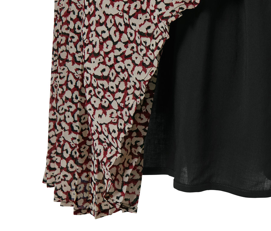 Detailansicht eines Maxi-Kleids mit Muster und schwarzem Stoff.