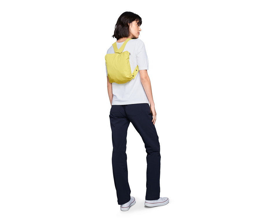 Frau trägt eine gelbe Lightweight-Regenjacke »pack me« als Rucksack.