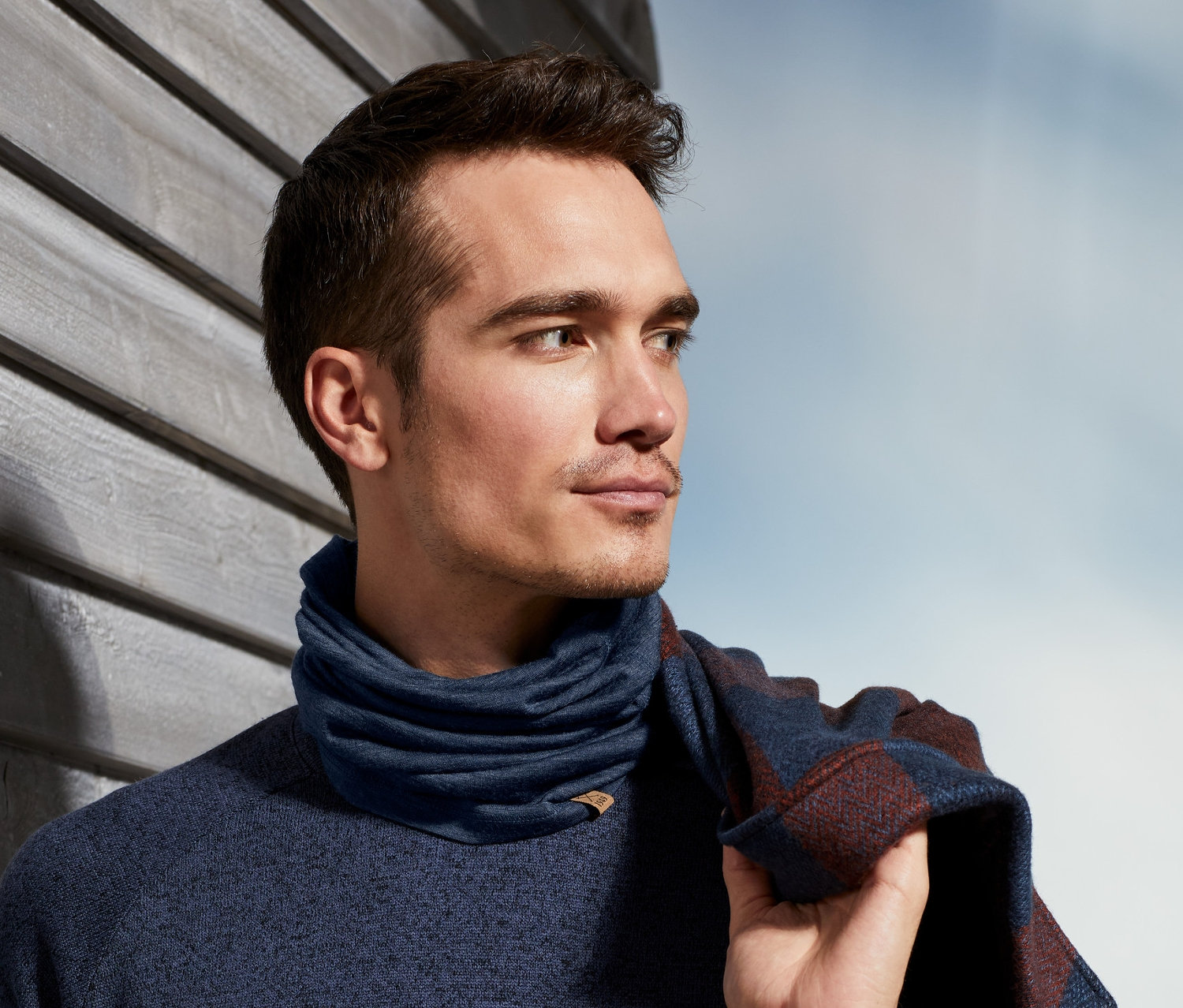 Mann mit dunkelblauem Pullover und Multifunktionstuch aus Merinowolle.
