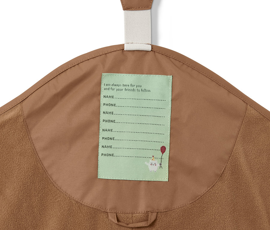 Detailaufnahme einer braunen Thermo-Regenhose mit einem Etikett für Name und Telefonnummer.