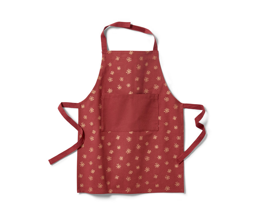 Eine rote Kinderschürze mit goldenem Schneeflockenmuster.