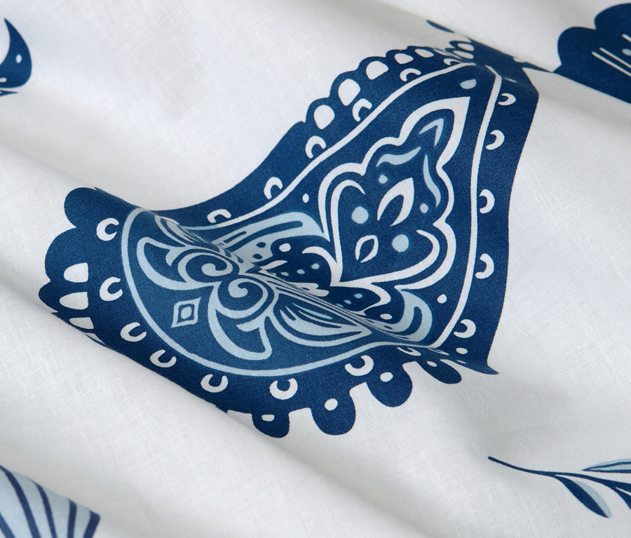 Nahaufnahme von weißer Renforcé-Bettwäsche mit blauem Paisley-Muster.