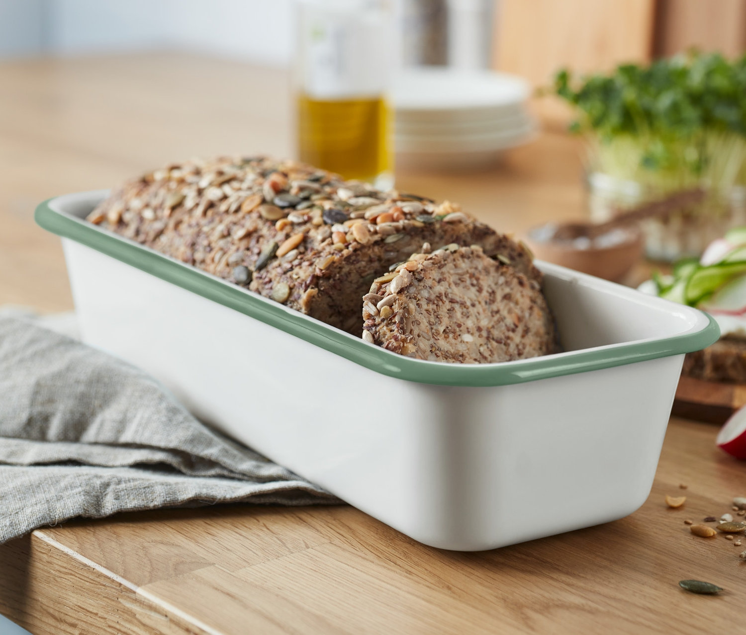 Brot in Emaille-Kastenform steht auf einem Holztisch.