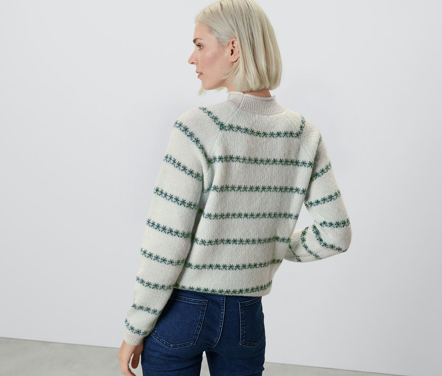 Frau von hinten trägt einen Strickpullover mit blauen Mustern.