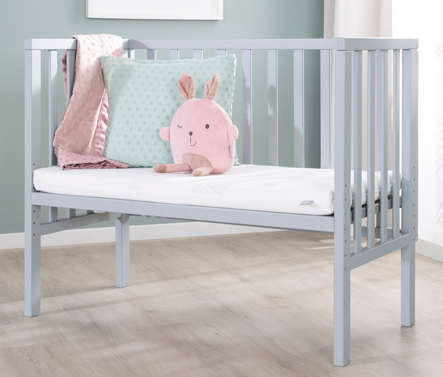 Ein hellblaues Kinderbett mit einem rosa Stoffhasen, einem Kissen und einer Decke. Im Bett liegt ein roba 2-in-1-Beistellbett »safe asleep®«, taupe.