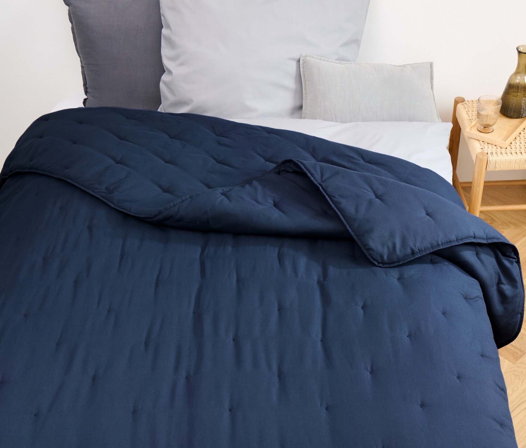 Blaue Tagesdecke liegt auf einem Bett.