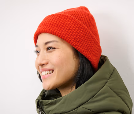 Lächelnde Frau mit orangefarbener Strickmütze.
