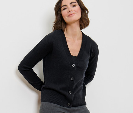 Frau posiert in Feinstrick-Cardigan mit Cashmere und grauer Hose.
