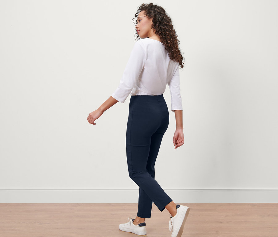 Frau geht, trägt eine dunkelblaue Stretchhose.