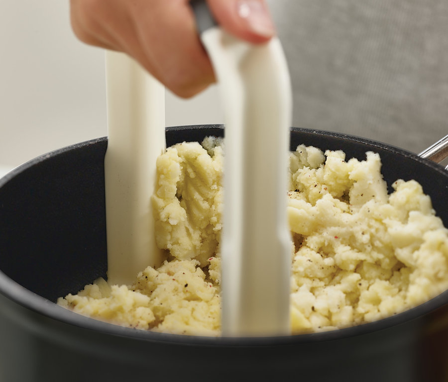 Person verwendet Joseph Joseph Kartoffelstampfer »Easy-Mash« in einem Topf mit Kartoffelpüree.