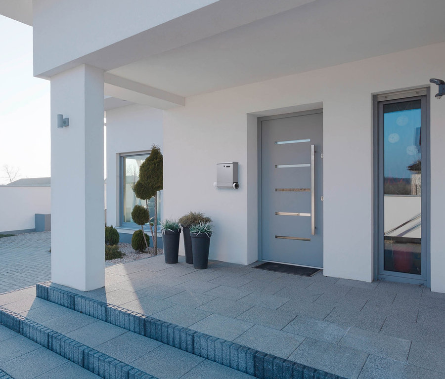 Eingang zu modernem Haus mit grauer Tür und silbernem AMARE Briefkasten mit Zeitungsfach.