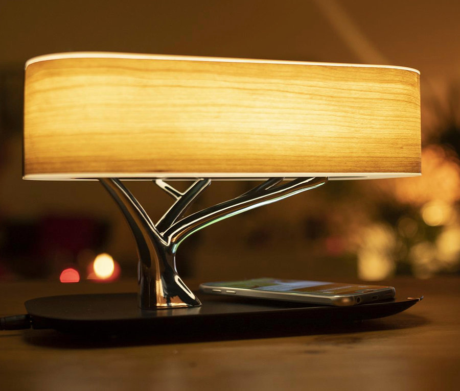 Induktive Ladestation mit BT-Lautsprecher und Lampe auf einem Tisch. Ein Smartphone liegt auf der Station.