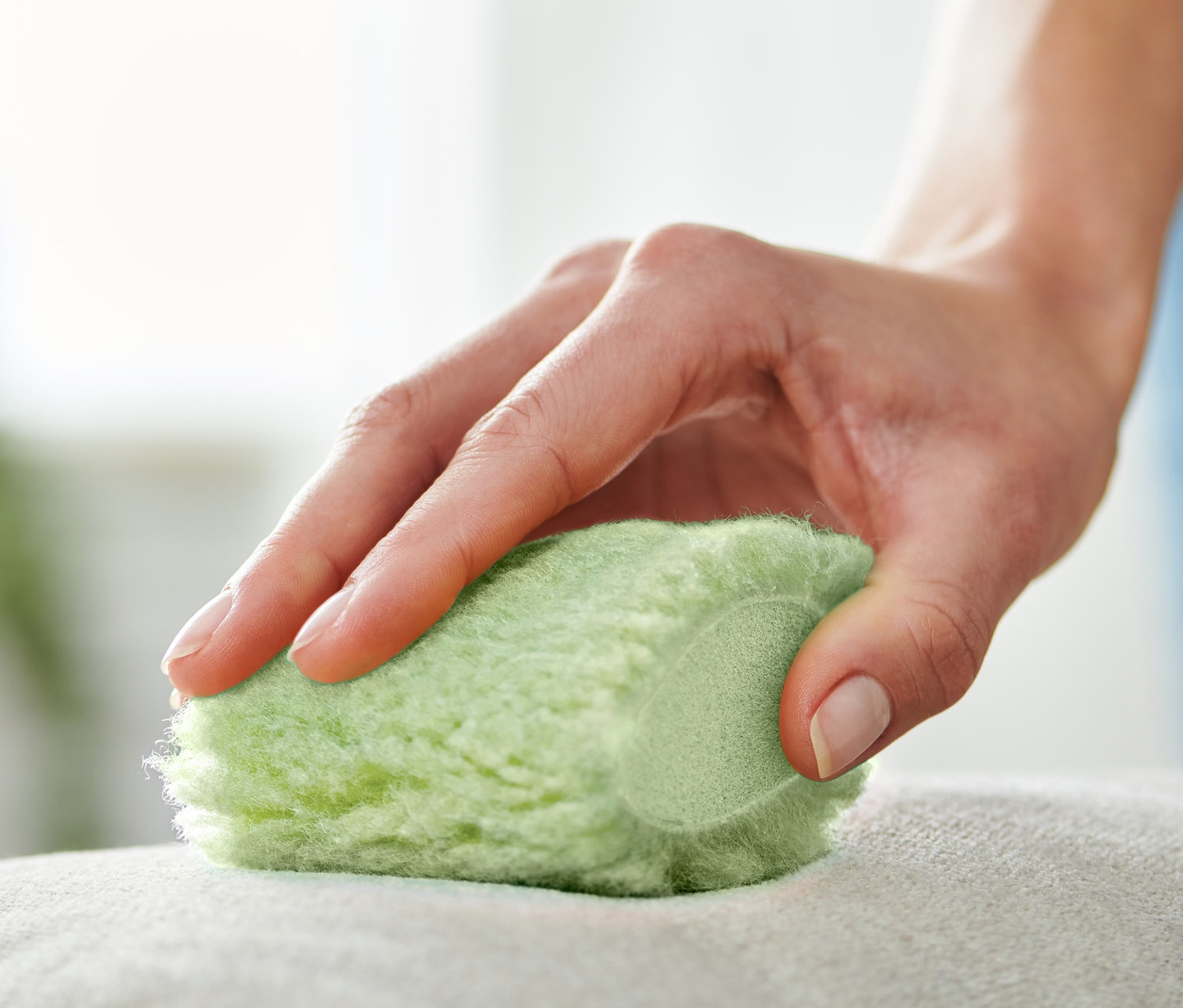 Eine Hand benutzt 2 Fleckenmäuse zur Reinigung eines Kissens.