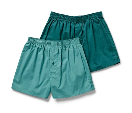 Zwei Web-Boxershorts, eine helltürkis mit Knopf, die andere dunkeltürkis.