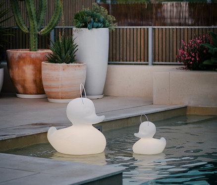 Zwei Goodnight Light LED-Leuchten »Ente« in verschiedenen Größen schwimmen im Pool.