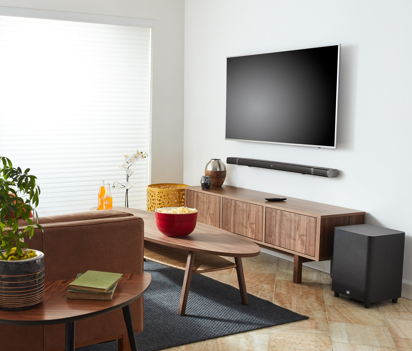 Wohnzimmer mit braunem Sofa, Fernseher und JBL BAR 5.1 Soundbar.