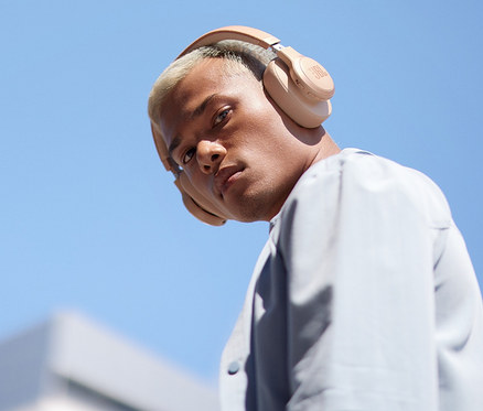 Junger Mann mit blonden Haaren trägt sandsteinfarbene JBL Live 770 NC Over Ear-Kopfhörer.