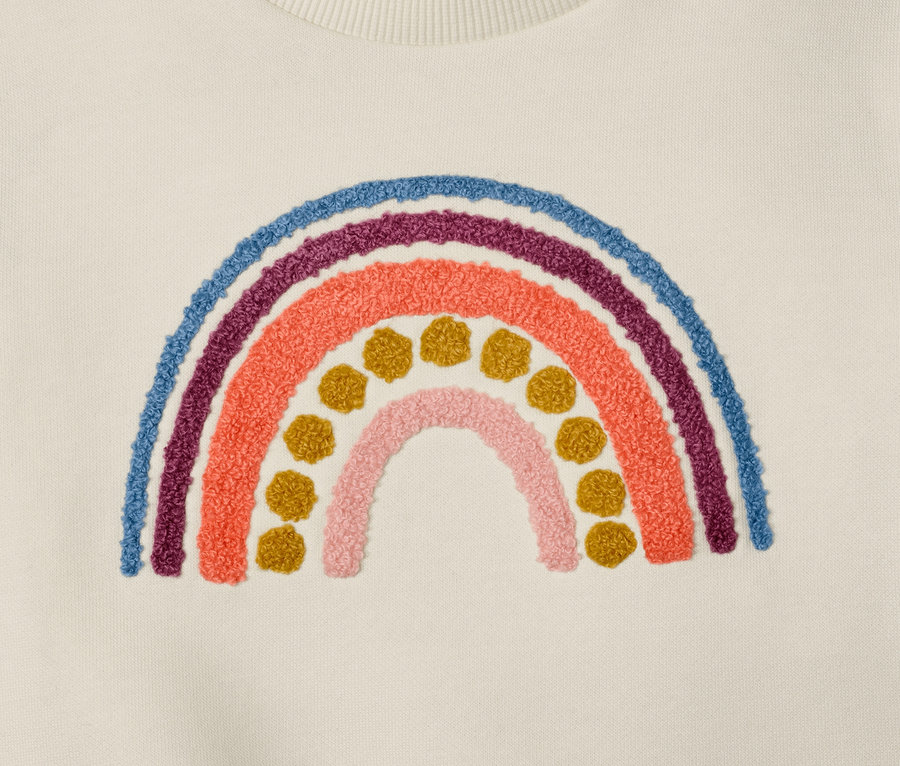Detailansicht eines Kinder-Sweaters mit Regenbogen-Applikation.