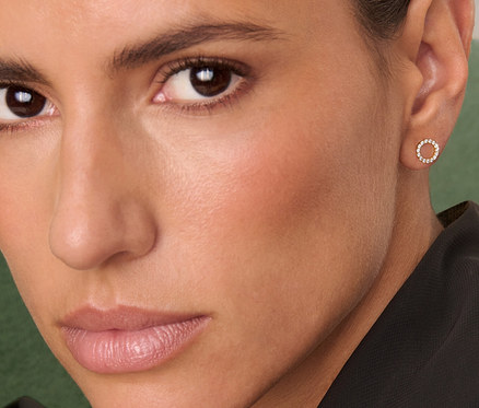 Porträt einer Frau mit braunen Haaren, die 375 Gold Ohrstecker Circle Zirkonia trägt.