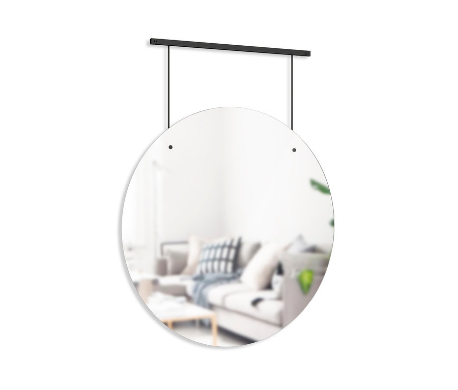 Ein runder Umbra Wandspiegel hängt an einer schwarzen Stange. Im Spiegel spiegelt sich ein Wohnzimmer.