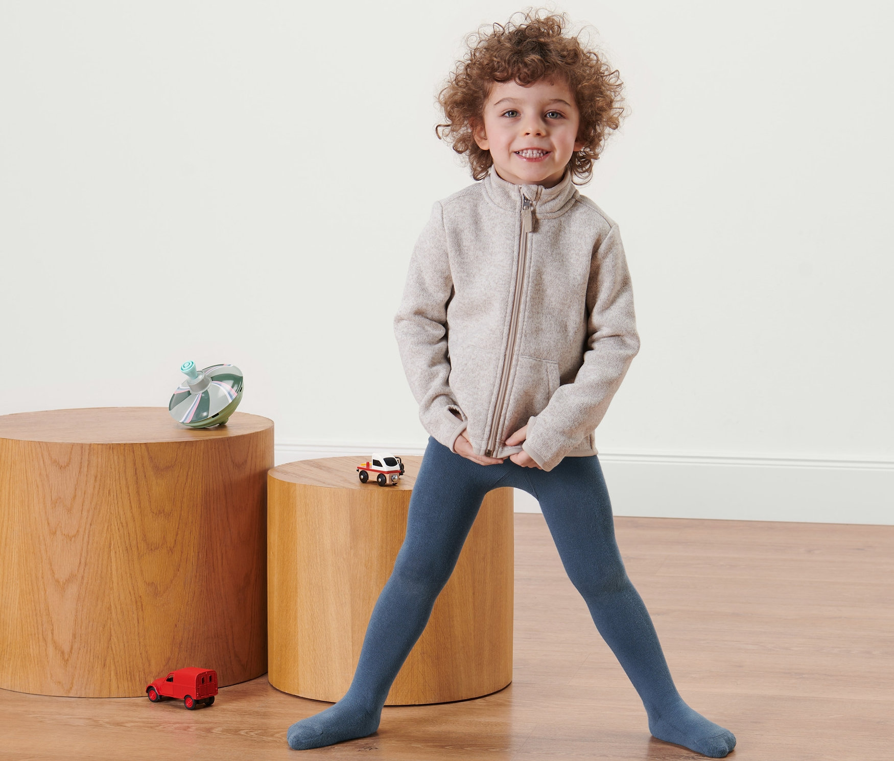 Ein Kind steht und trägt blaue Baumwollstrumpfhosen.