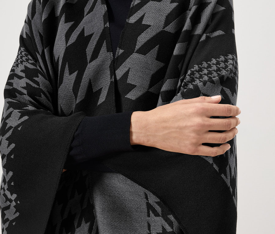 Frau trägt einen schwarz-grauen Umhang mit Hahnentrittmuster.