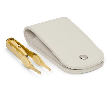 Eine goldene Pinzette liegt neben einem offenen, weißen Etui.