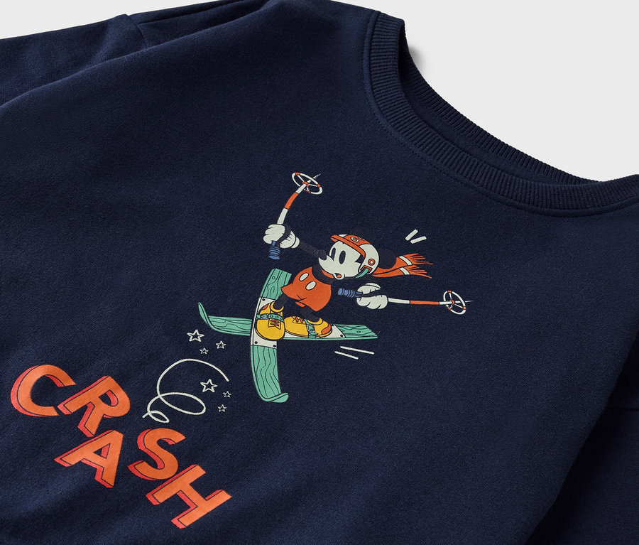 Auf einem marineblauen Sweatshirt ist ein Cartoon von Mickey Mouse beim Skifahren abgebildet.