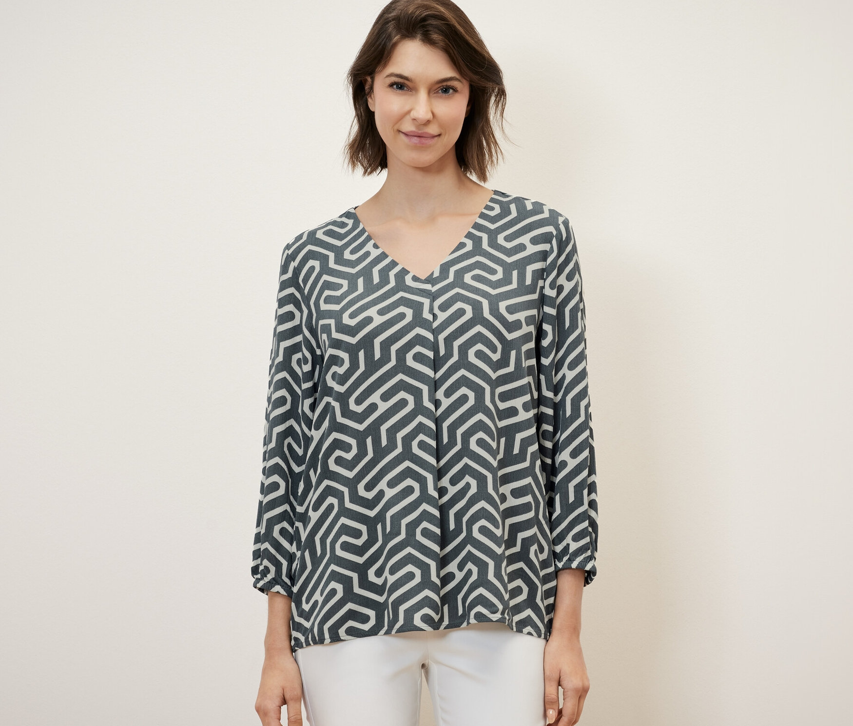 Frau trägt eine Bluse in Crinkle-Optik und weiße Hose.