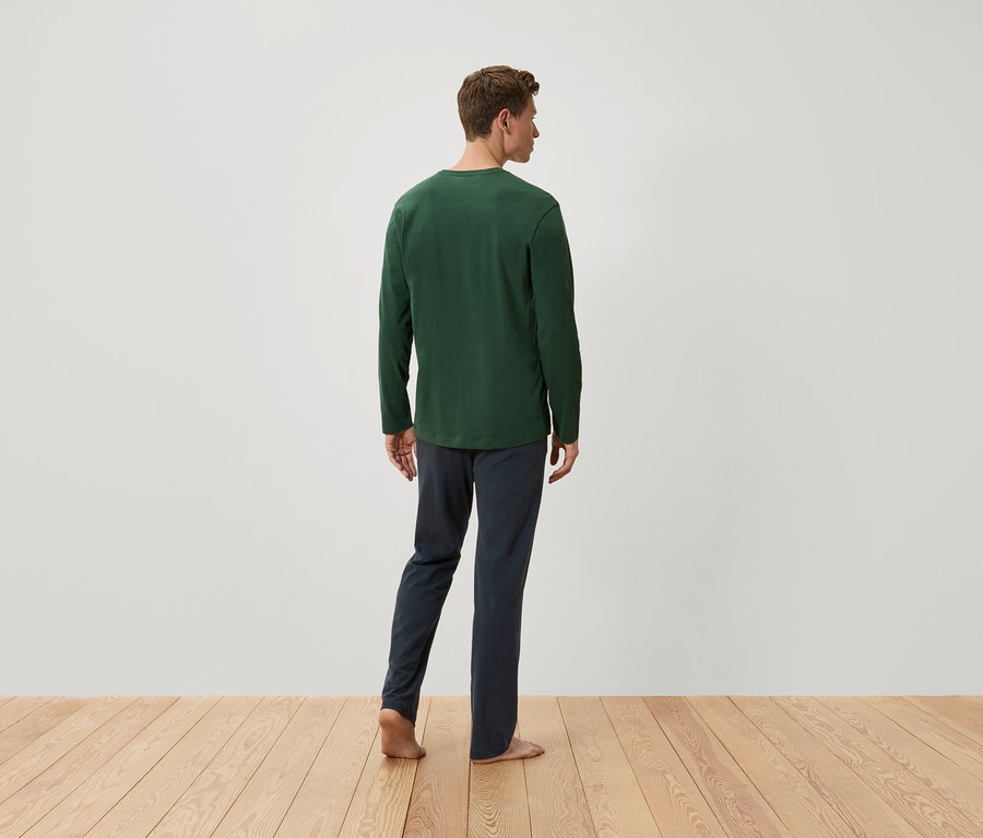 Mann von hinten trägt ein grünes Langarmshirt und dunkelblaue Hosen.
